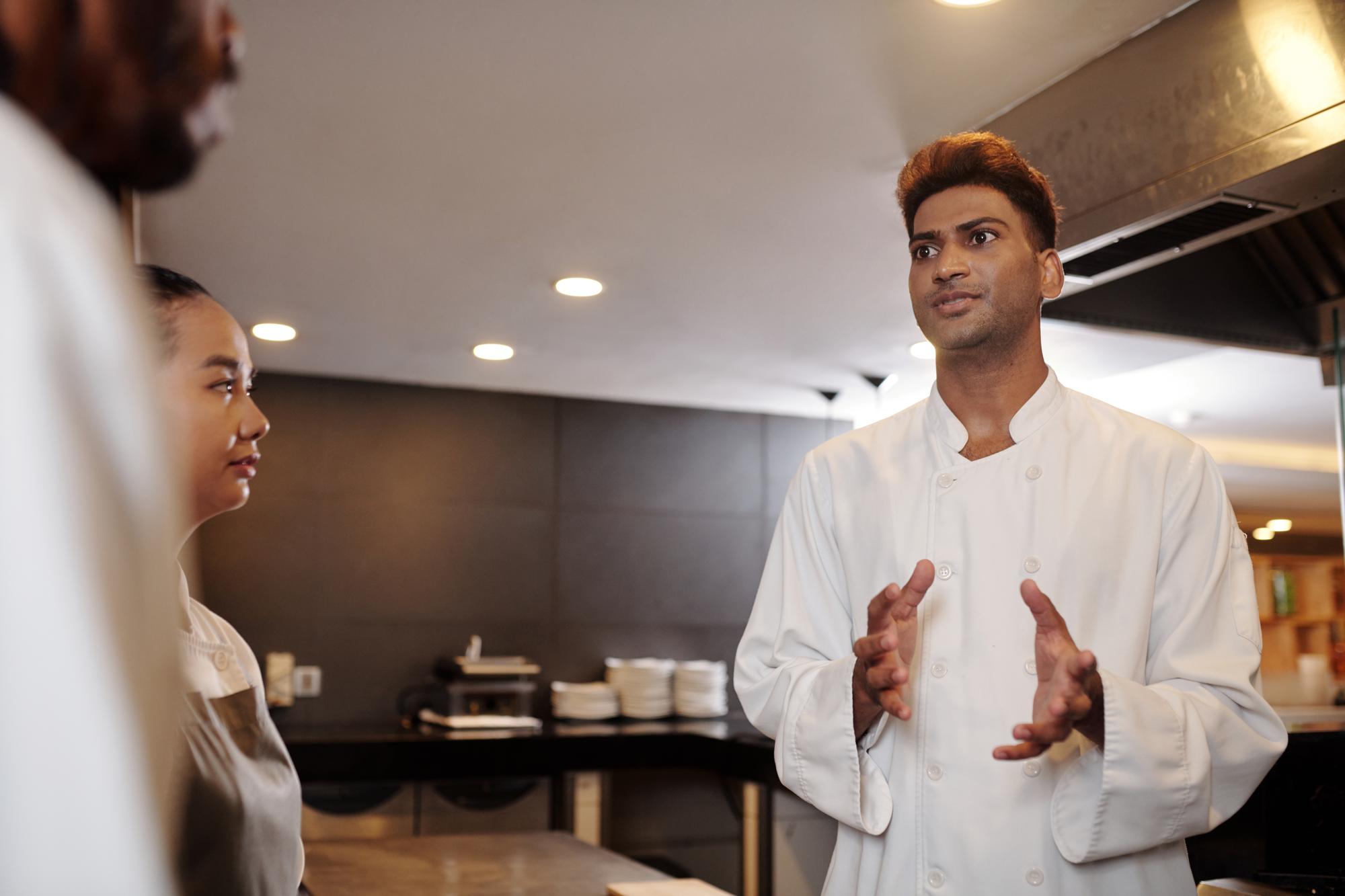 Chef consulting with team in modern kitchen